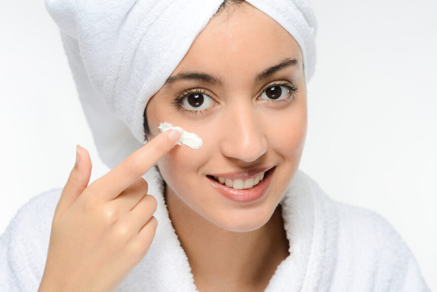 Young women putting cream on face